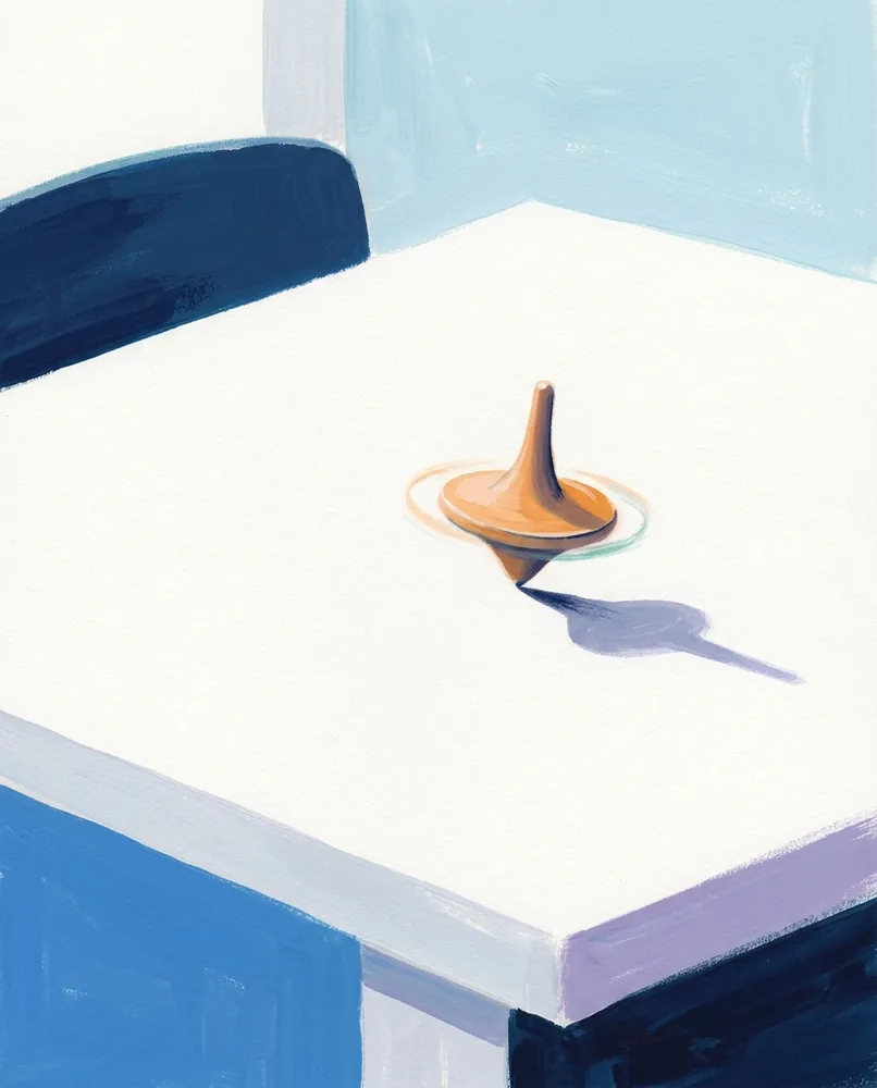 A wooden spinning top turns on a bare tabletop, with a blurred rim and a long shadow beside it.